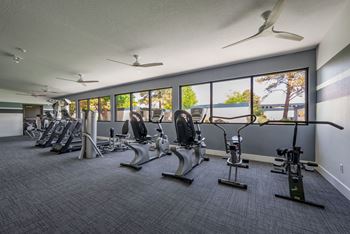 a room filled with lots of cardio equipment and a large window